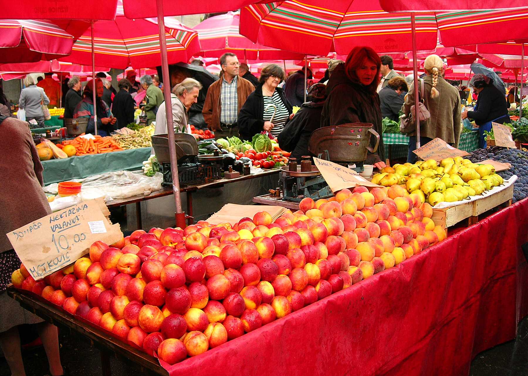 Étals de pêches et de nectarines sous les parasols rouges du marché de Dolac, à Zagreb