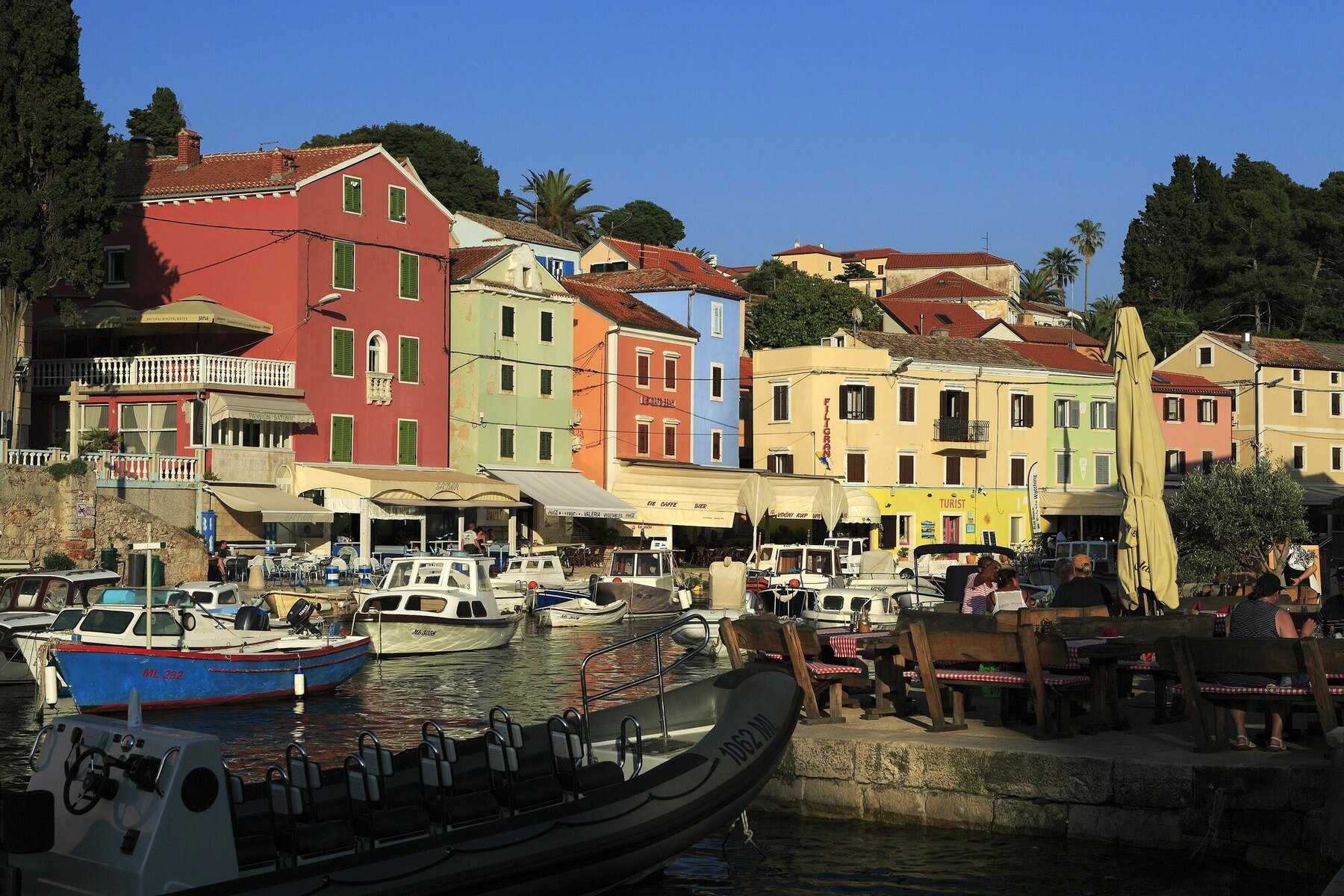 Terrasses de restaurants et façades colorées autour du petit port de Veli Lošinj, en fin de journée