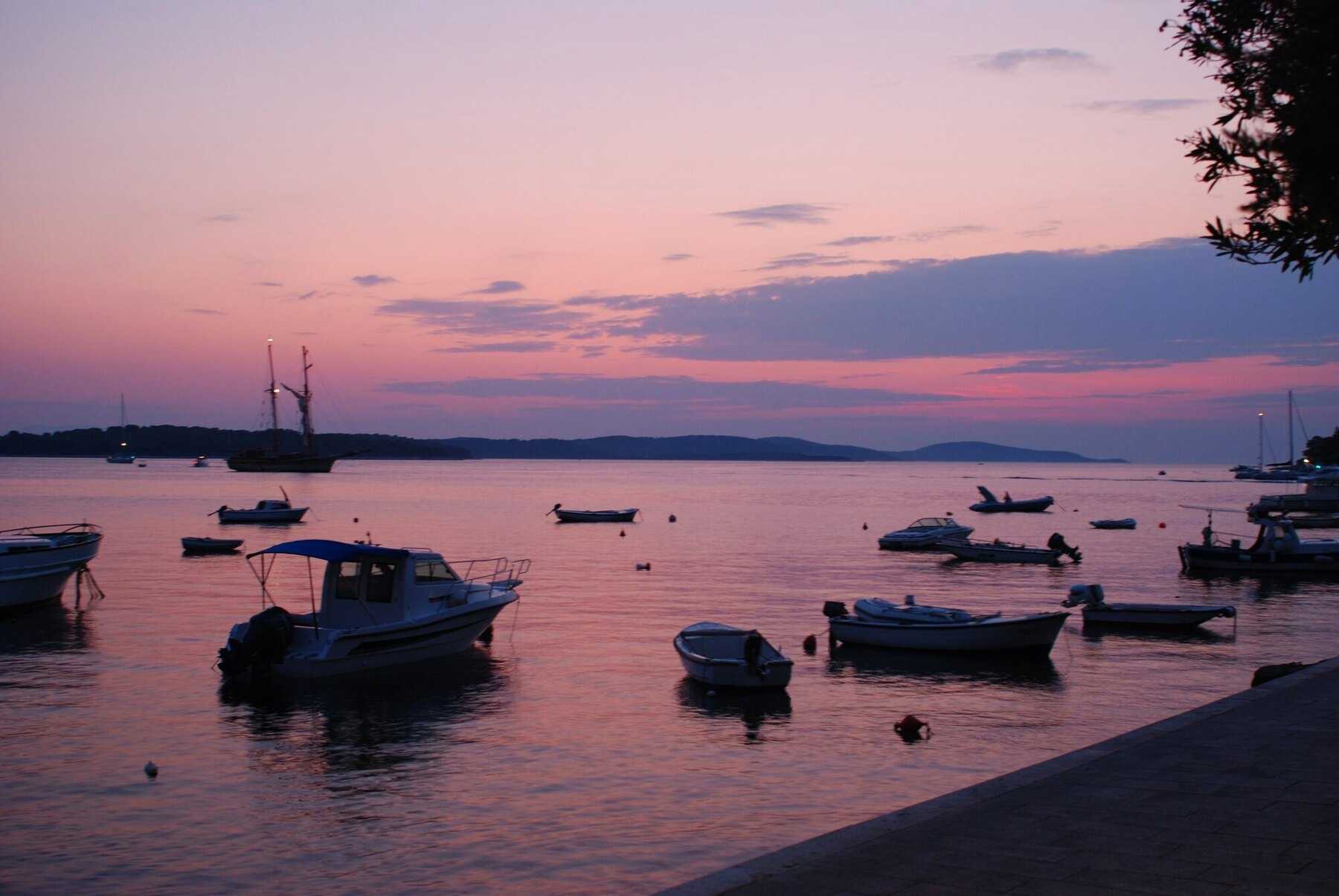 Coucher de soleil rose sur le port de Hvar ville et ses barques