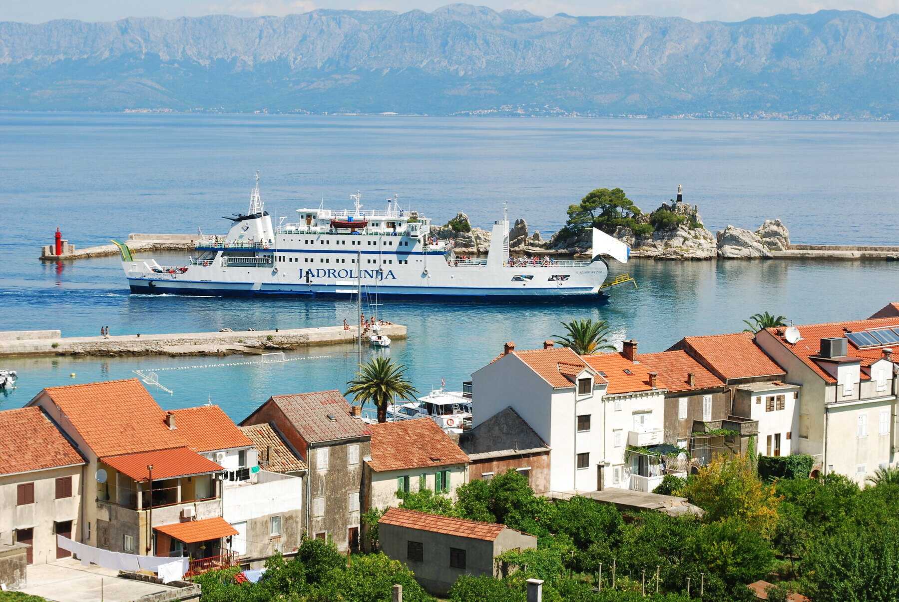 Un car-ferry Jadrolinija entre dans le petit port de Trpanj, sur la presqu'île de Pelješac, avec le continent à l'horizon