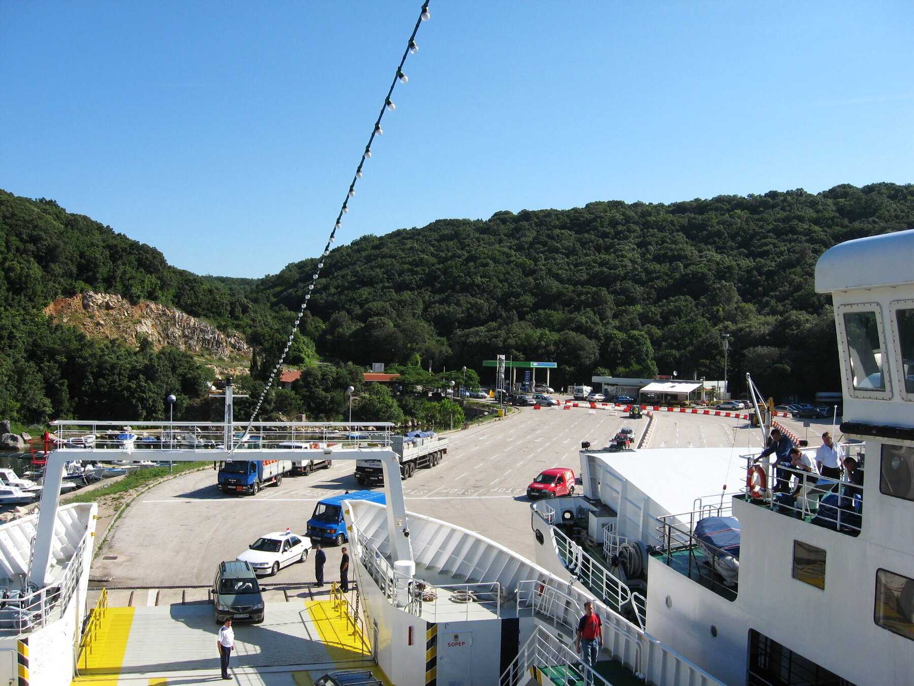 Voitures en file sur le quai de Valbiska, sur l’île de Krk, vues depuis le pont d’un car-ferry
