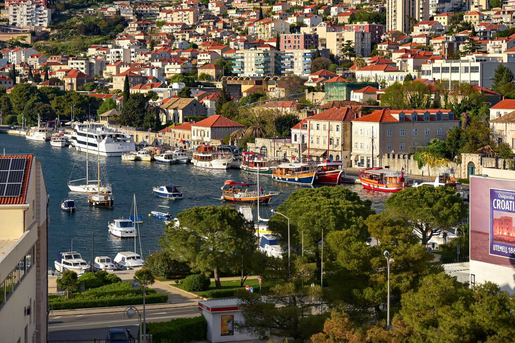 Le port de Gruž, à Dubrovnik, avec ses bateaux d’excursion amarrés le long du quai et le quartier sur la colline
