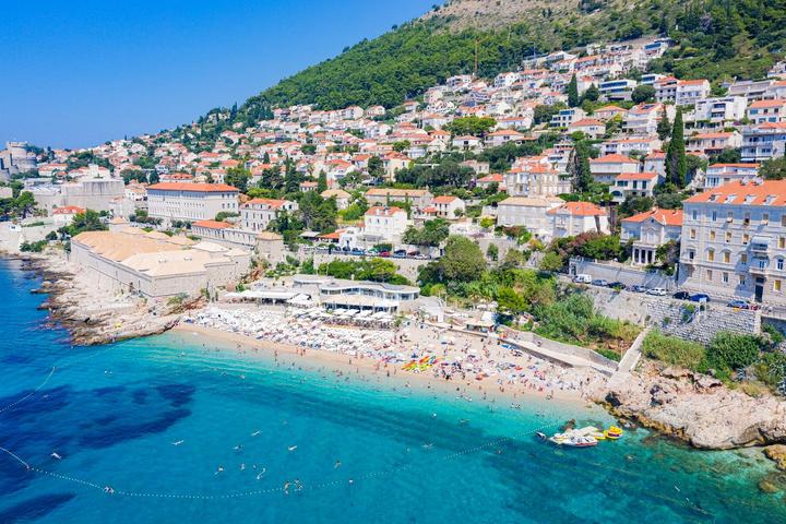 La plage de Banje vue du ciel, avec ses transats, l’eau turquoise et le quartier de Ploče sur la colline
