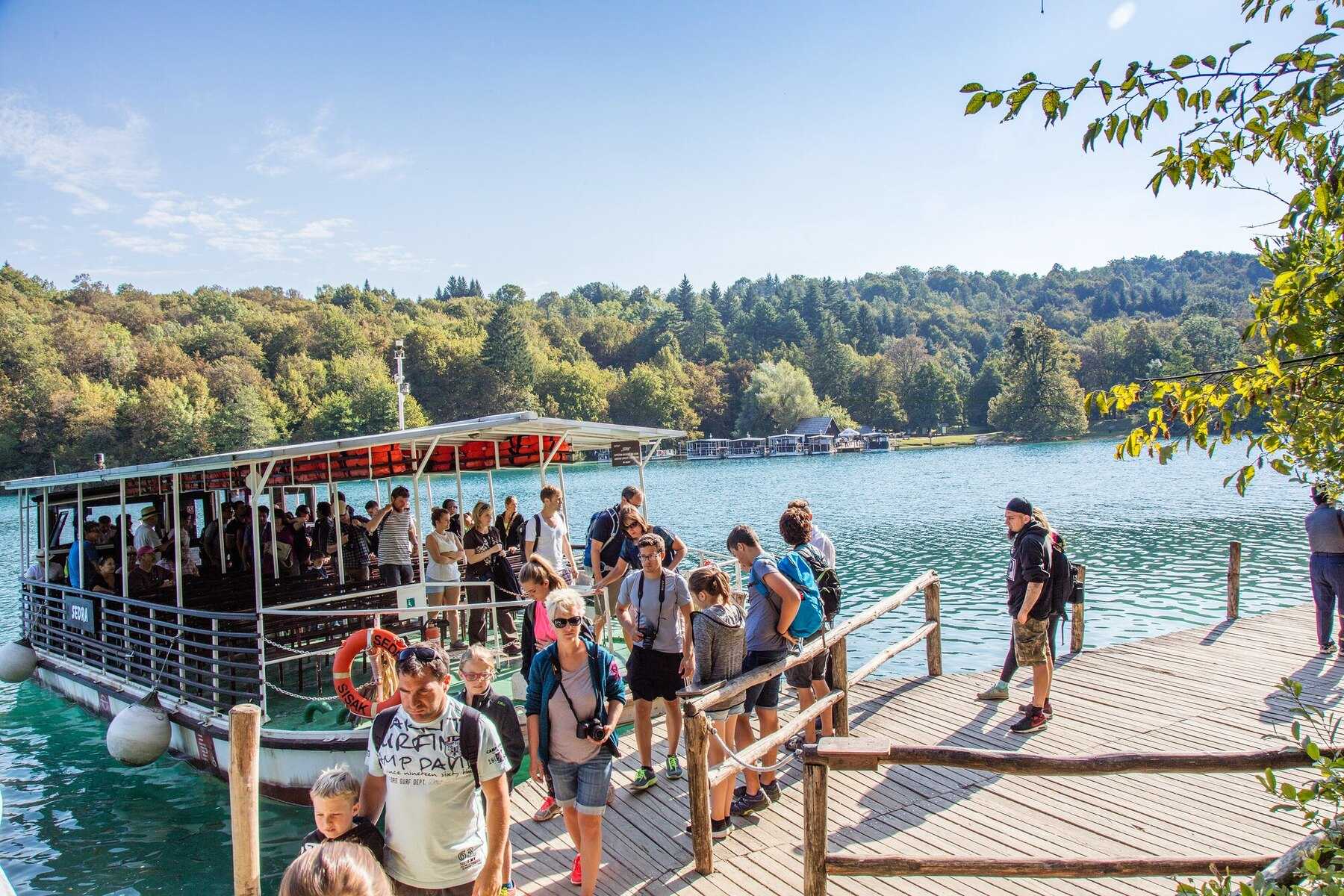 Visiteurs débarquant du bateau électrique sur un ponton du lac Kozjak