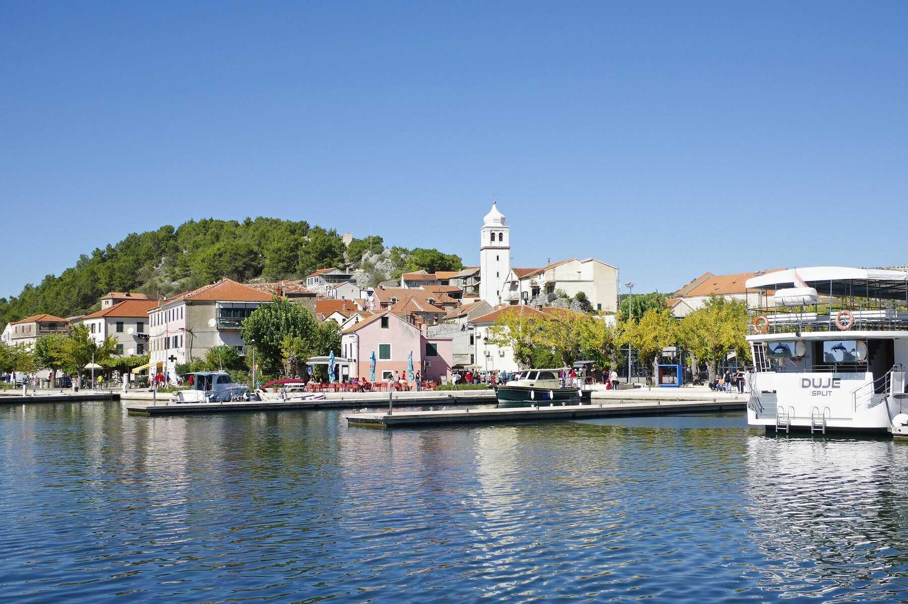Le quai de Skradin et sa vieille ville au bord de la Krka, avec un bateau amarré