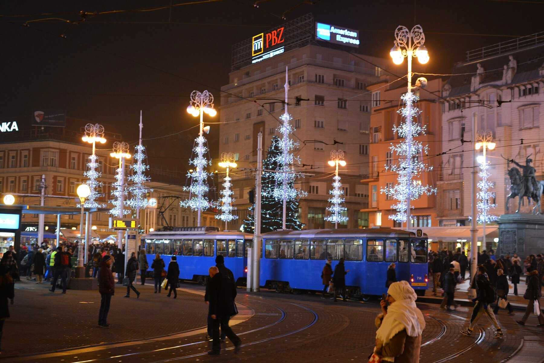 Place Ban-Jelačić à Zagreb illuminée pour l’Avent, avec ses tramways bleus et ses sapins lumineux