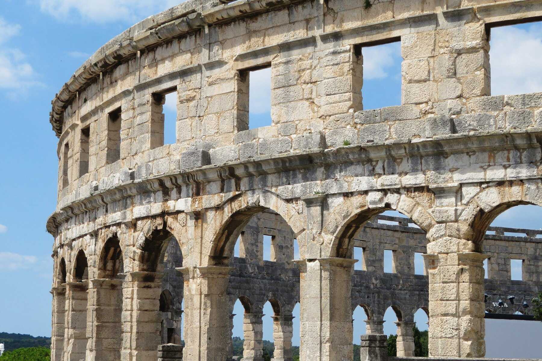 Les arcades de l'amphithéâtre romain de Pula sous un ciel bleu