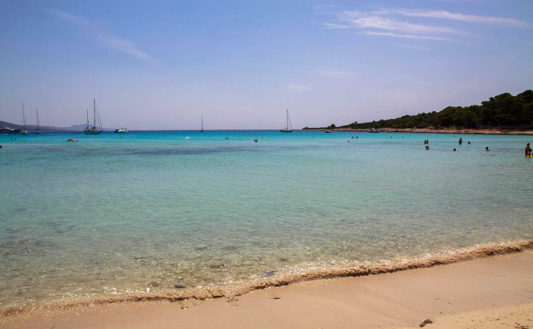 Le sable et l'eau turquoise de la baie de Sakarun, sur Dugi Otok, avec des voiliers au mouillage