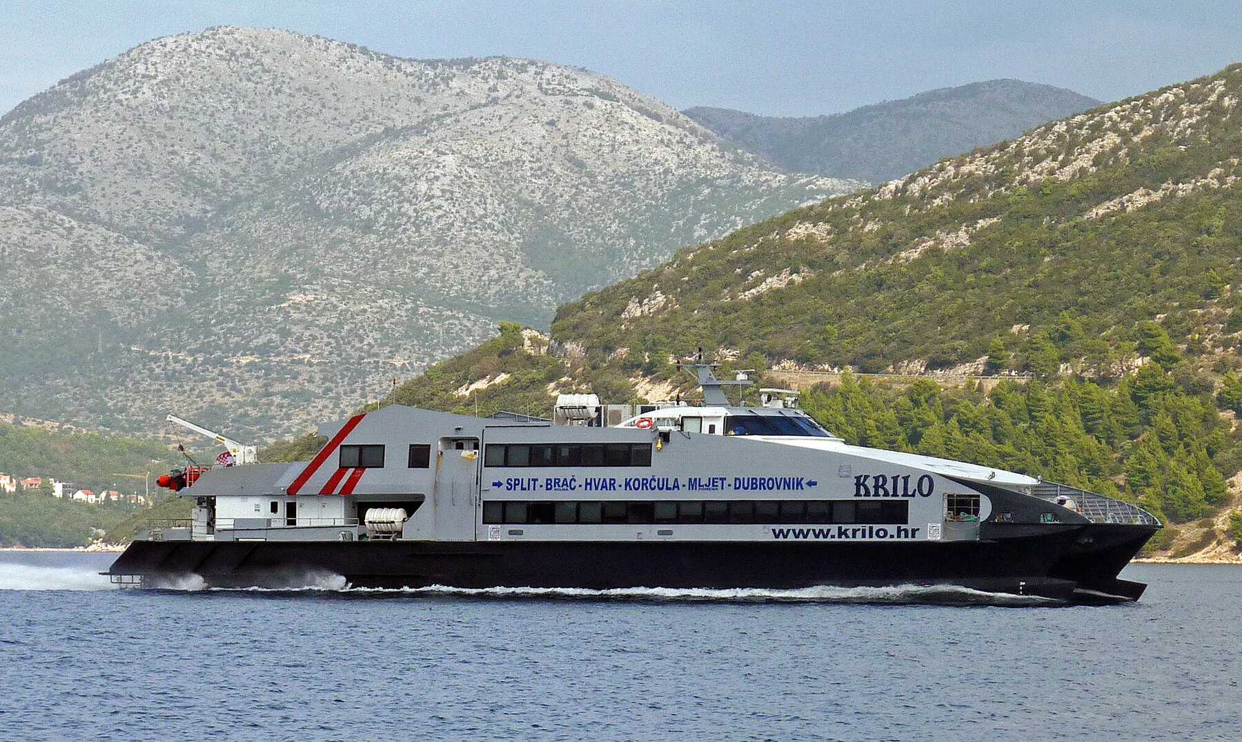 Le catamaran Krilo de la ligne Split–Dubrovnik longe une côte boisée de Dalmatie