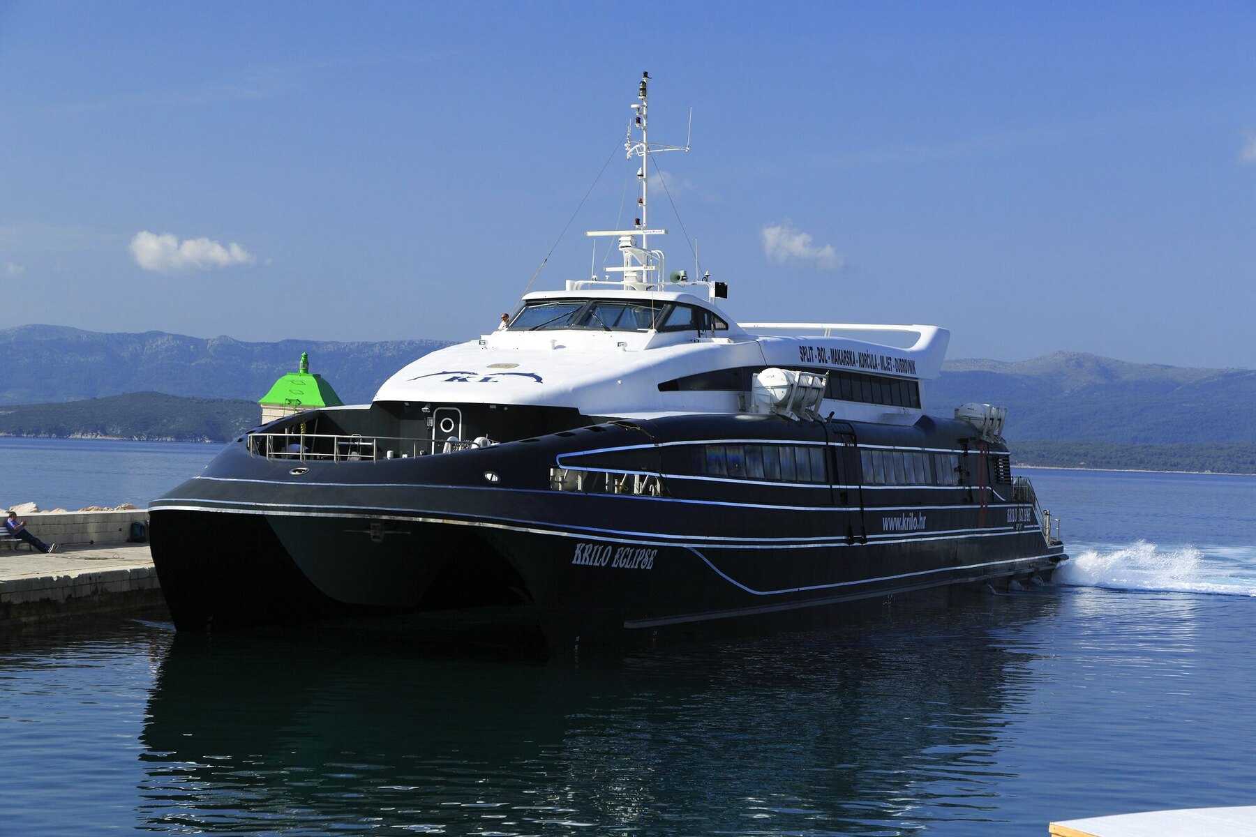 Le catamaran Krilo Eclipse, à coque noire, amarré à un quai sous le ciel bleu de Dalmatie