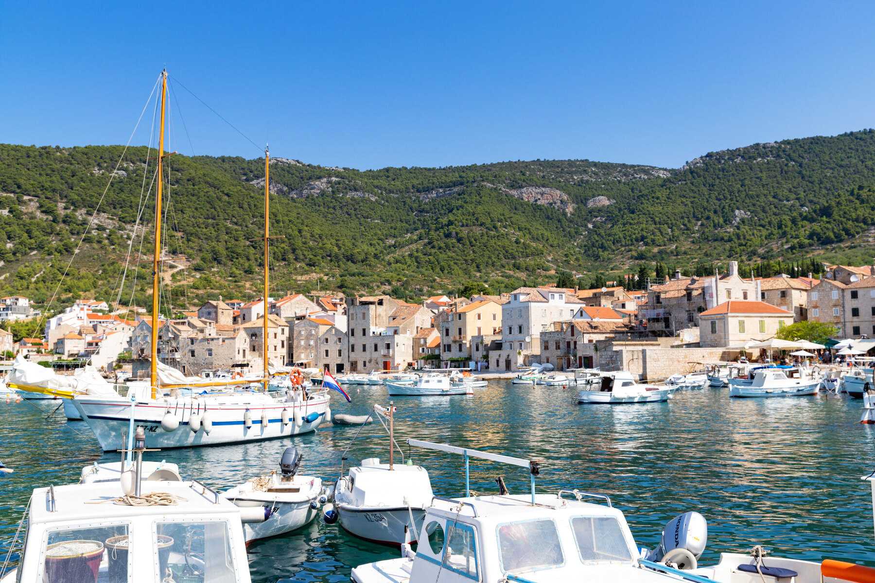 Le port de Komiža, à l'ouest de l'île de Vis, avec ses voiliers et ses maisons de pierre au pied des collines