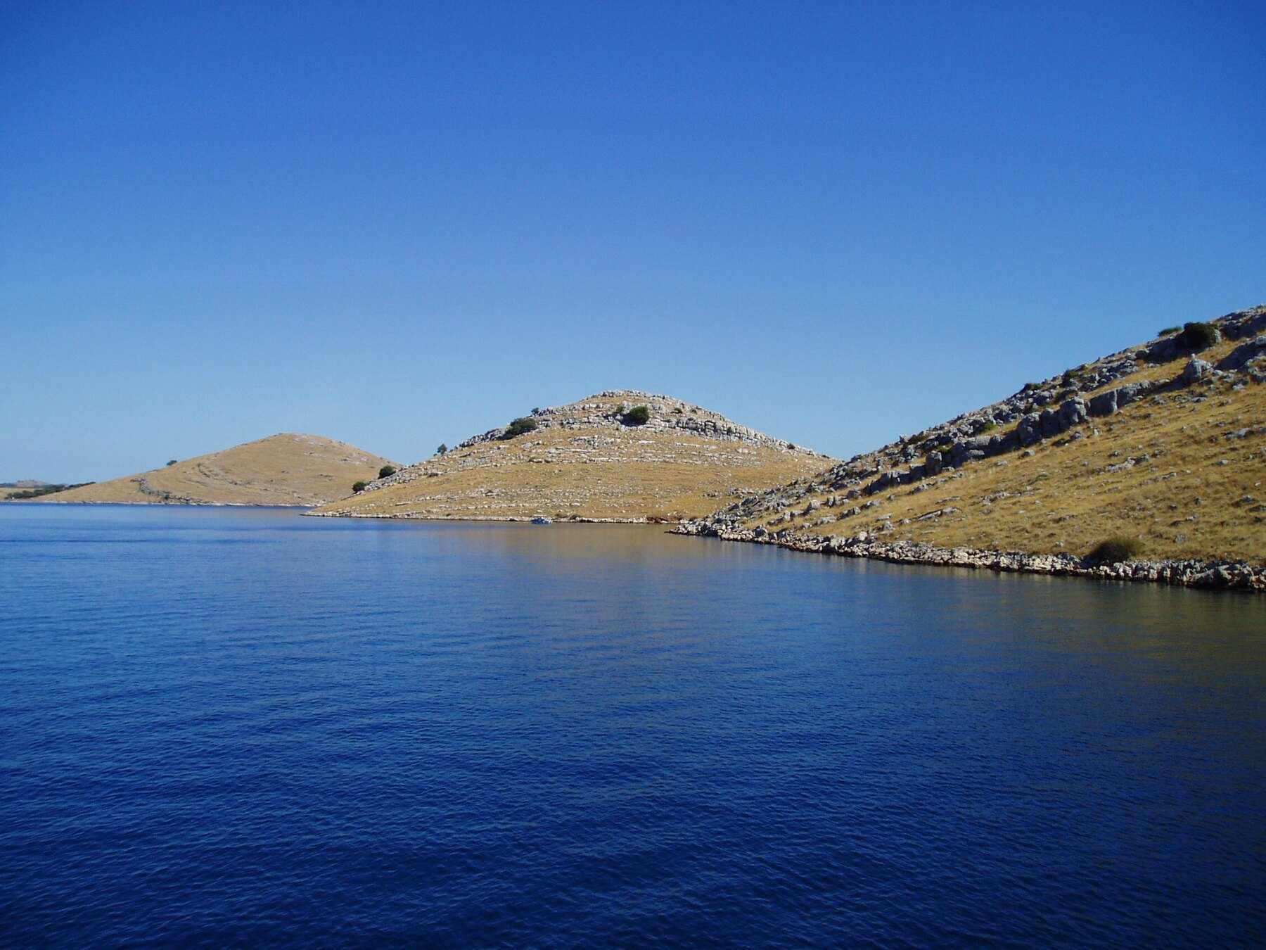 Collines pelées des îles Kornati au-dessus d'une mer d'un bleu profond