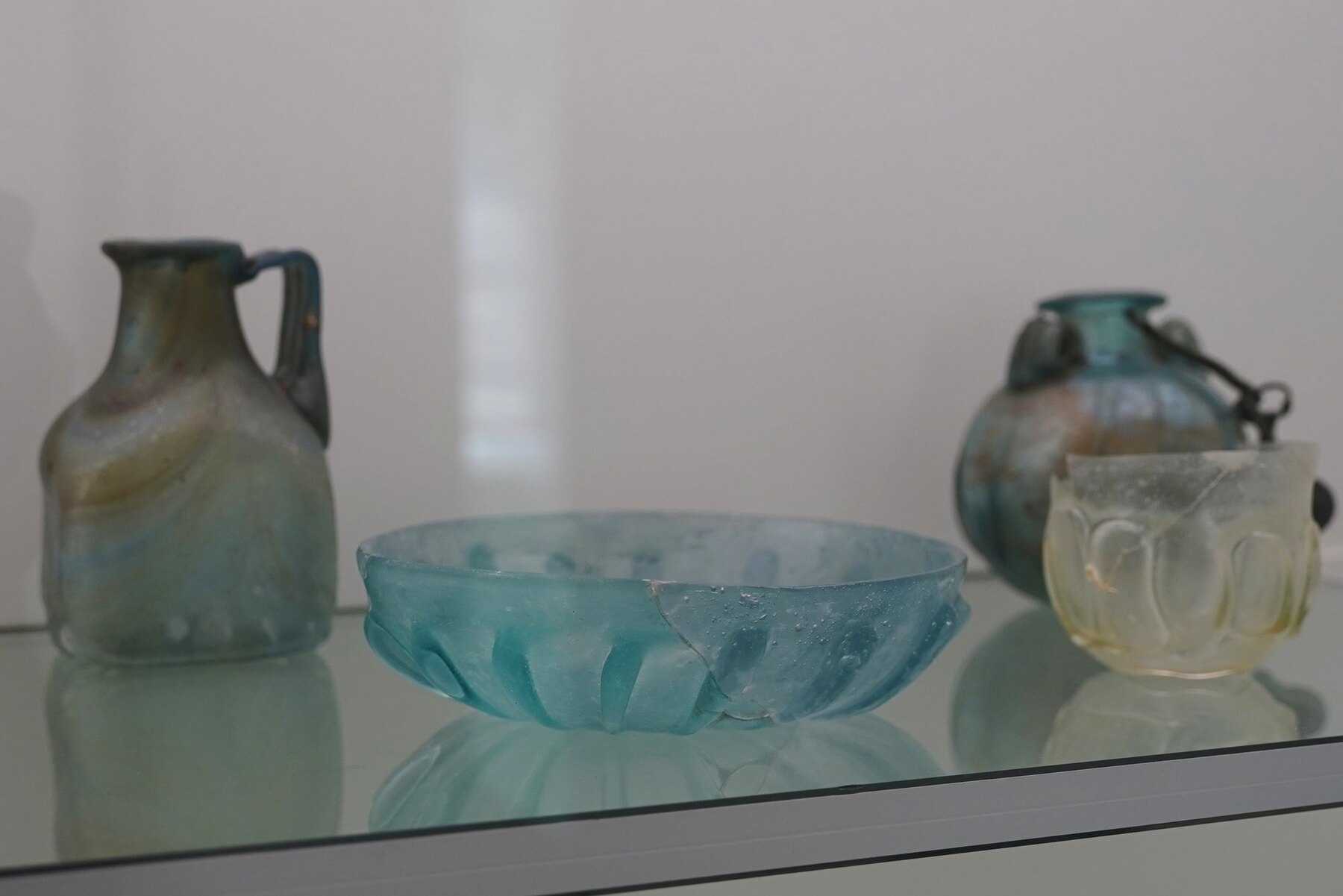 Flacons et coupe de verre romains dans une vitrine du musée du Verre antique